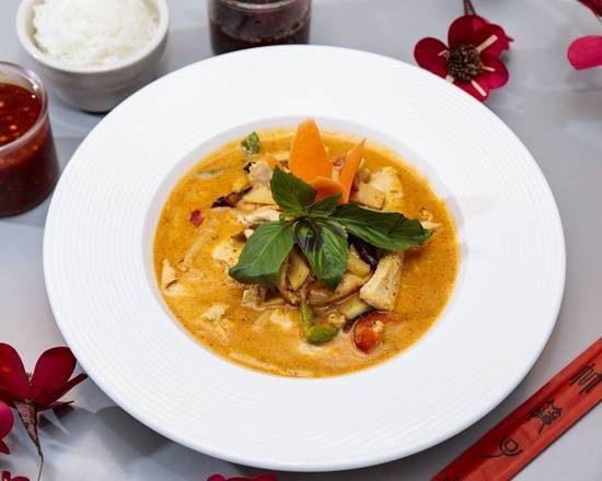 Red curry with basil and bell peppers in a white bowl